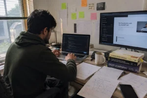 Student learning AI and machine learning programming from online courses in 2026 with laptop and study materials