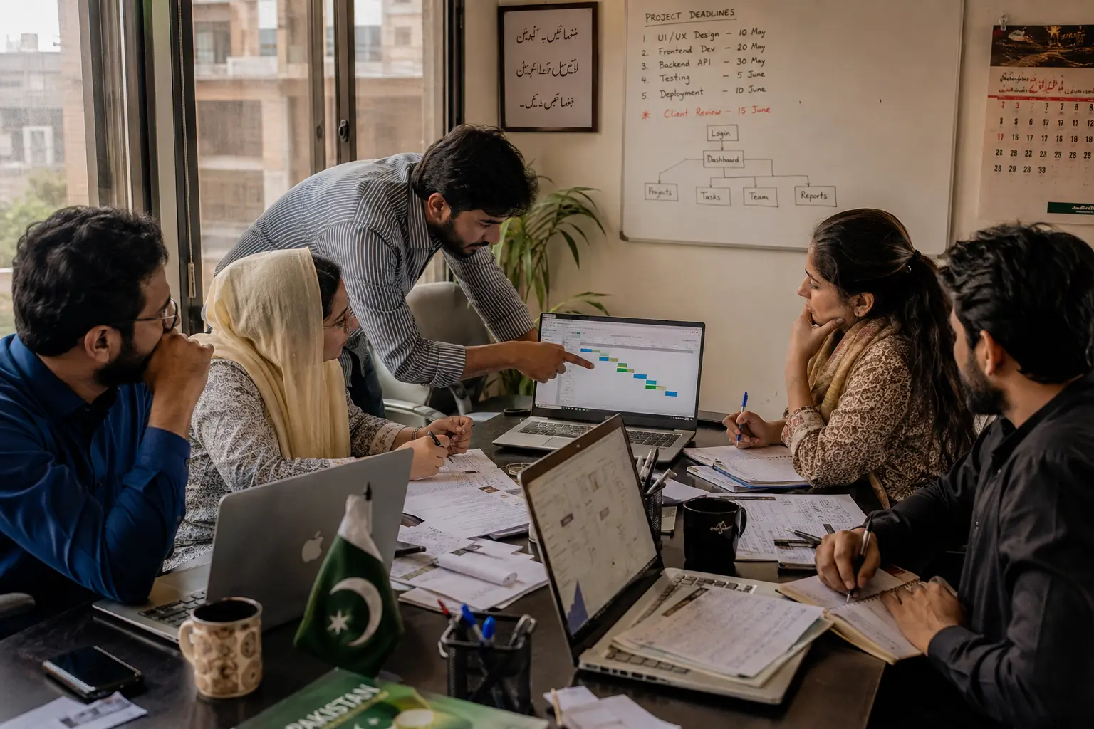 "Pakistani small business team collaborating on project management software selection around conference table with laptops displaying task boards and project timelines in Karachi office"