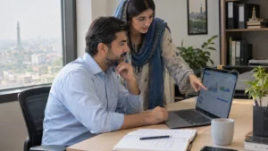 Pakistani business professionals reviewing custom accounting software with FBR compliance dashboard on laptop in modern office